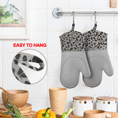 Grey silicone oven mitts hanging by their loops on a kitchen rail
